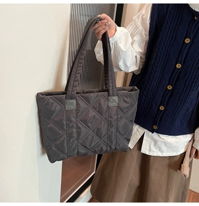Dettaglio borsa shopper trapuntata grigio scuro con trama a rombi sulla spalla della modella