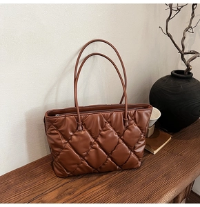 Macro detail of caramel brown quilted tote bag showing plush texture and drawstring design