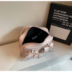 Detail of pink glossy leather bag showing black interior lining and bow pockets