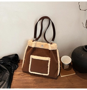 Detailed close-up of brown suede tote with soft fleece trim and metallic hardware accents
