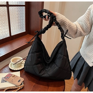 Detail of black quilted nylon bag with elegant pleated handle and diamond lattice texture