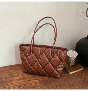 Detail of a brown quilted tote bag on a wooden table with vintage interior decor