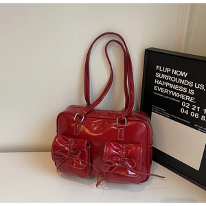 Macro shot of red patent leather shoulder bag with decorative bows and cargo pockets