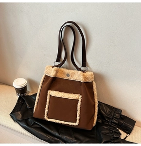 Detail of lamb wool trim and leather handles on brown tote bag over a black jacket