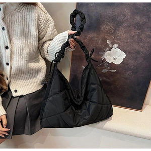 Detail of black quilted nylon hobo bag featuring a unique ruched handle and puffer texture