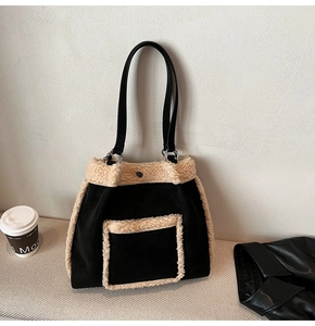 Close-up of black suede tote bag with beige faux shearling trim and front pocket detail