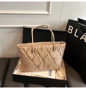 Detail view of a beige quilted tote bag presented in a luxury gift box with silk lining