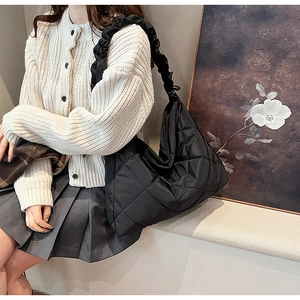 Close-up of black quilted nylon bag featuring a stylish ruched cloud-style shoulder strap