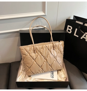 Macro detail of beige quilted tote bag in premium gift box with polished leather finish
