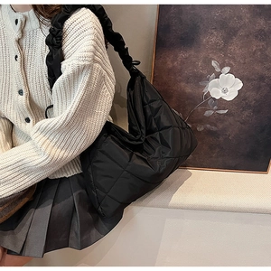 Detail of black quilted nylon bag featuring a unique ruched shoulder strap and diamond pattern