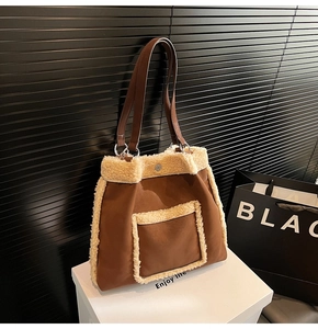 Detail of magnetic buckle and faux shearling trim on brown tote bag over a white platform