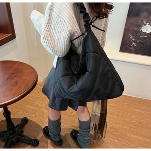 Detailed view of black quilted nylon hobo bag with ruched strap on model in cozy interior
