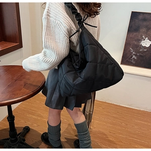 Detail of black quilted nylon tote with ruffled shoulder strap and bow knot decoration