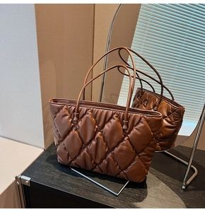 Detail of a brown quilted tote bag with glossy rhombus texture and sleek shoulder straps