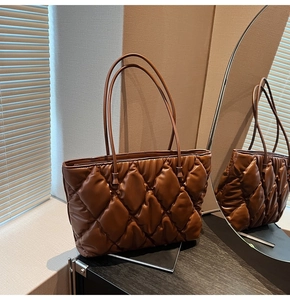 Detail of dark brown quilted puffer tote bag showing glossy leather texture and stitching