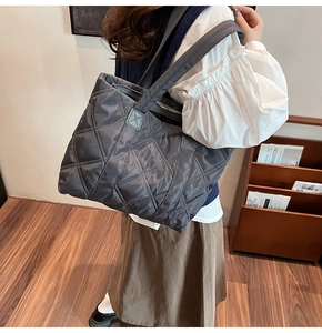Vista dettagliata di una borsa tote in nylon trapuntato grigio scuro indossata da un modello