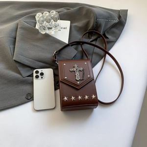 Vintage brown crossbody bag with silver gothic cross and star studs on grey blazer background