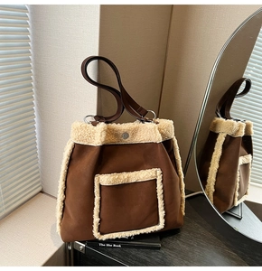 Detail of a brown suede tote bag with cream fleece trim and magnetic closure design