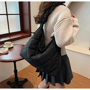 Detail view of black quilted nylon tote bag with textured ruffles on the shoulder strap