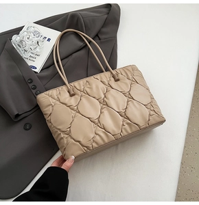 Detailed close-up of beige quilted puffy tote bag texture with elegant stitching