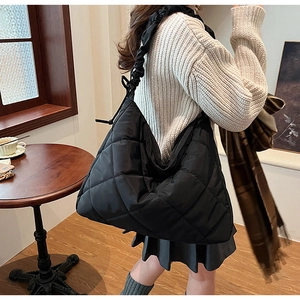 Detail of black quilted tote bag with shiny nylon finish and ruched shoulder strap