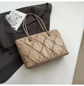 Close-up of beige quilted tote bag with bubble texture and round slim handles