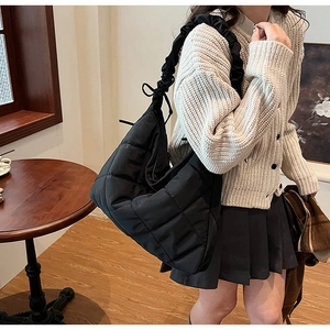 Detail of black quilted nylon hobo bag with unique ruffled strap on female model