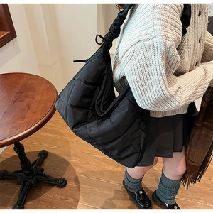 Detail of black quilted shoulder bag featuring unique gathered handle and soft nylon texture