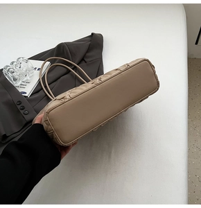 Detail view of the flat base and stitching of a beige quilted leather tote bag