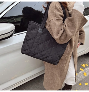 Dettaglio della borsa tote trapuntata nera leggera con motivo a rombi in una strada
