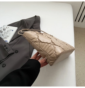 Detailed close-up of a beige quilted tote bag with soft diamond stitching and urban style