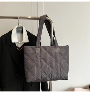 Macro detail of charcoal grey quilted nylon tote bag featuring reinforced shoulder straps