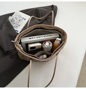 Top view of spacious beige quilted tote bag interior showing books, umbrella and essentials