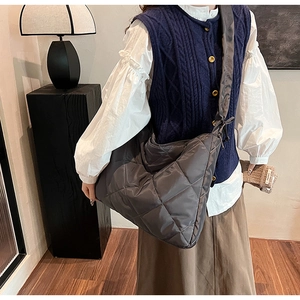Deep grey oversized quilted tote bag with wide shoulder strap worn by a model