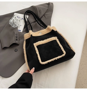 Detail of faux shearling trim on black suede tote bag against a minimalist background