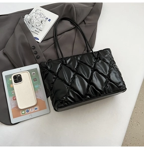Macro view of black quilted tote bag with polished PU leather texture and diamond stitching