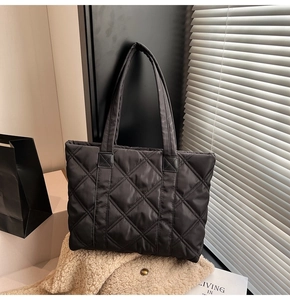 Close-up of black quilted nylon tote bag with rhombic stitching on soft beige fabric