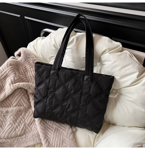 Detailed close-up of classic black quilted nylon tote bag featuring diamond stitch texture