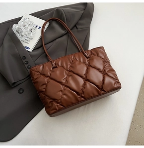 Detail of coffee brown quilted tote bag with diamond stitching on a grey blazer
