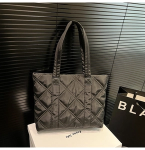 Close-up of black quilted nylon tote bag showing diamond stitching and puffy texture
