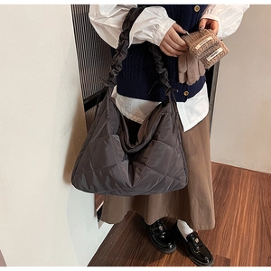 Detail of dark grey quilted tote bag featuring a textured ruffles shoulder strap style