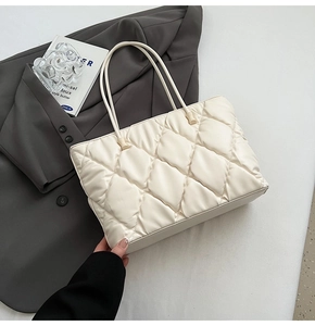 Detail of off-white quilted tote bag showing intricate diamond stitching and fine metal clasp
