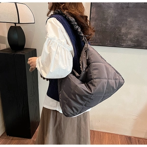 Detail of dark grey quilted nylon tote featuring ruched shoulder strap and diamond patterns
