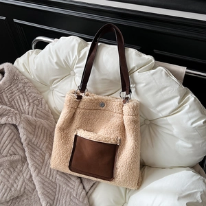 Close-up of beige teddy fleece tote bag featuring brown leather pocket and metallic hardware