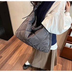 Detailed view of large quilted nylon tote bag in smoky grey with elegant pleated shoulder strap