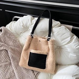 Close-up of beige shearling tote bag with black leather handle and metal ring connector