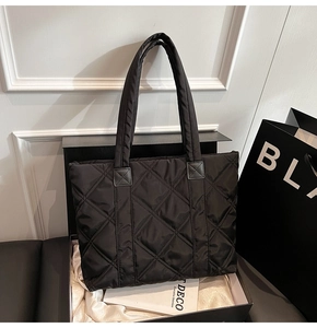 Dettaglio della borsa tote nera trapuntata a rombi presentata in una scatola regalo