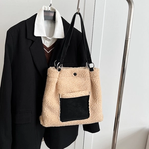 Close-up of shearling tote bag featuring a black pocket and leather straps with silver rings