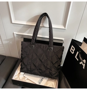 Detailed close-up of a black quilted nylon tote bag placed inside a premium gift box