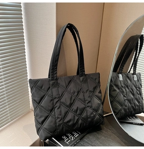 Close-up of the glossy black quilted nylon fabric and diamond embroidery on the tote bag